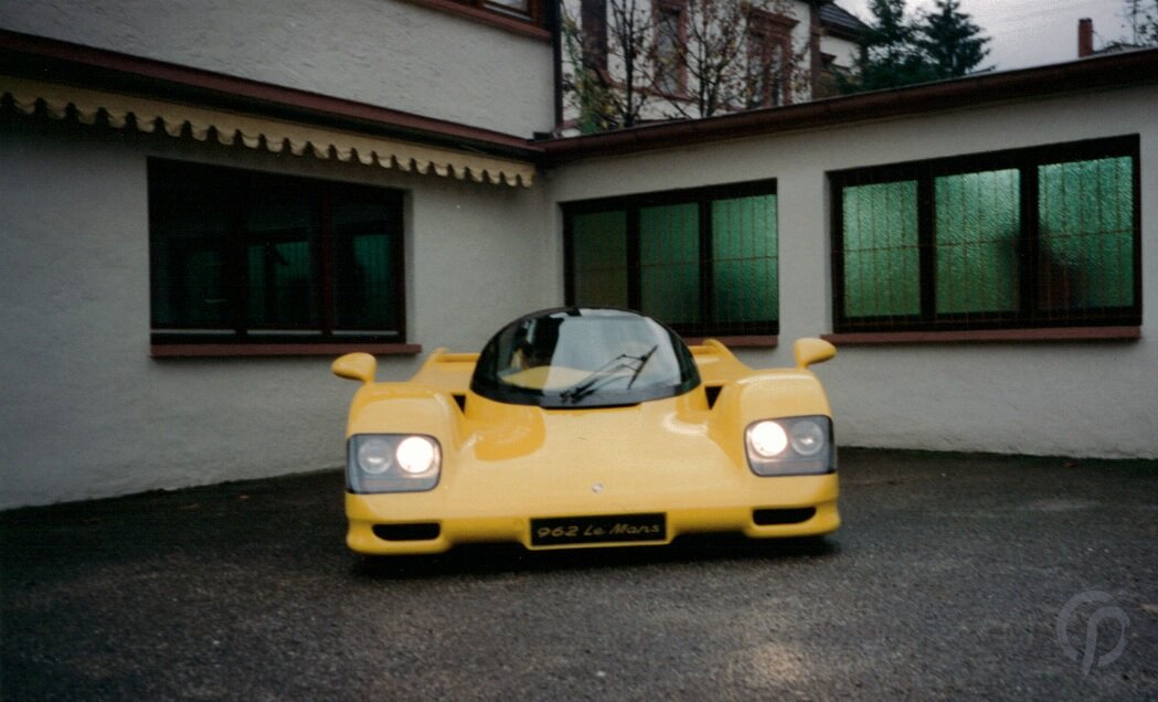 Dauer 962 Le Mans in gelb in der Frontansicht mit geschlossenen Flügeltüren auf dem Werkstattgelände