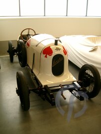 Der Austro Daimler Sascha Front und linke Seite in weiß mit roten Pik Zeichen parkend neben weiteren Fahrzeugen in unserer Werkstatt